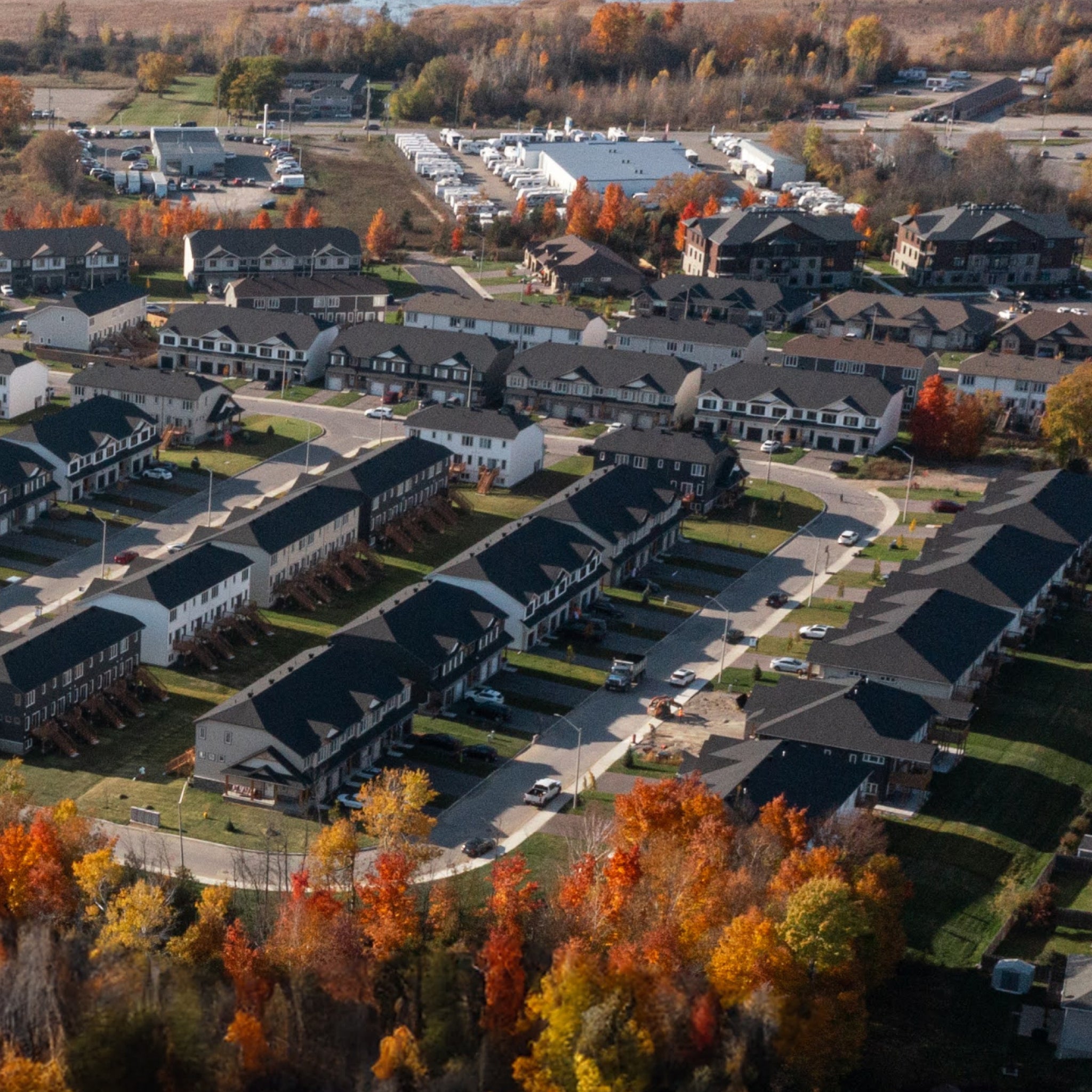 Aerial view of Bellamy Farm Community in Smiths Falls Phase 2, showing modern townhomes surrounded by vibrant fall foliage, showcasing the development's layout and scenic autumn landscape